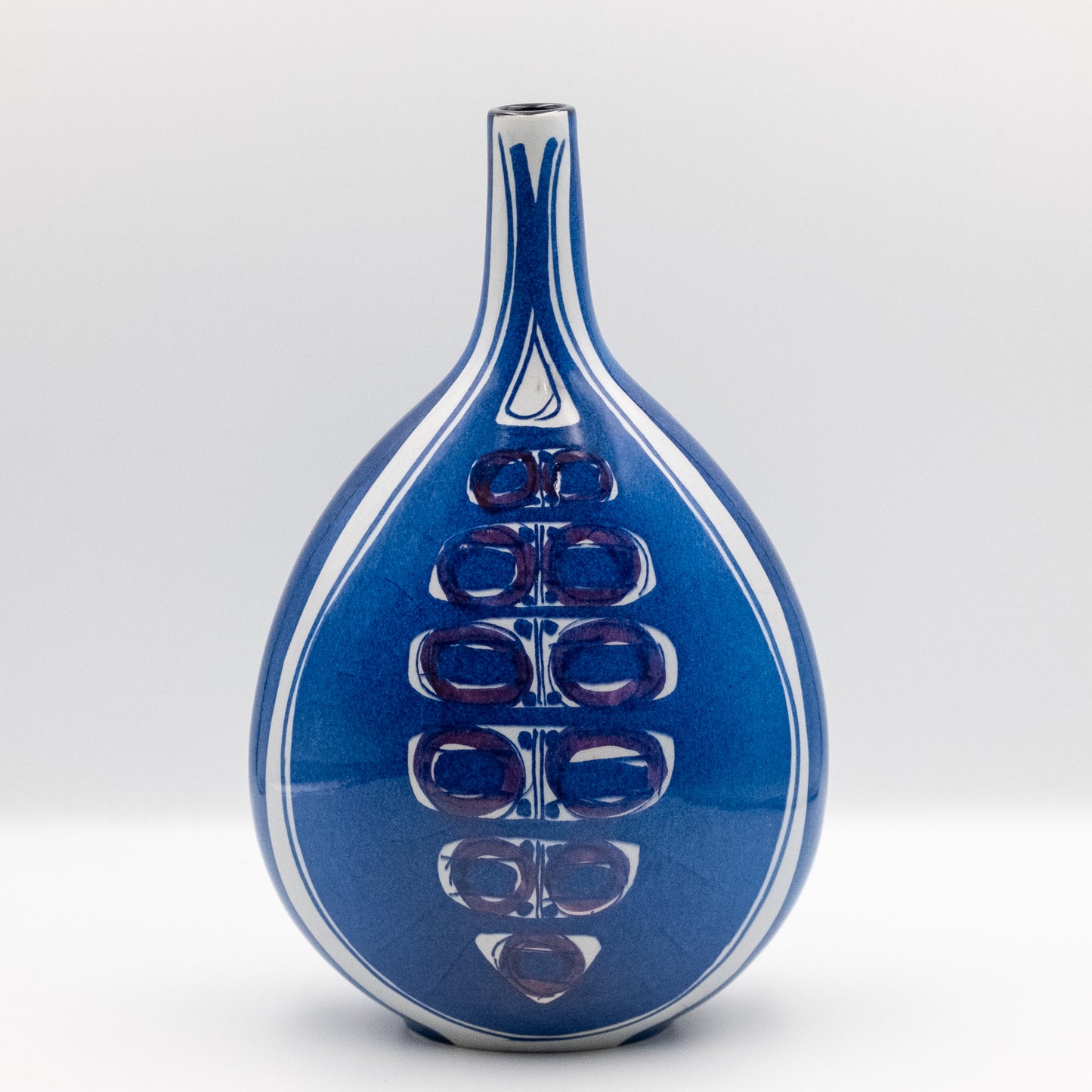 ロイヤルコペンハーゲン（Royal Copenhagen）「テネラ（Tenera）」シリーズのピローベース。インゲ・リセ・コエフォードがデザイン。底から細く伸びるネック、大胆な青地に白と紫で抽象化された「目」のモチーフが垂直に並ぶ。底にはアルミニアロゴとイニシャル「IK」。北欧ヴィンテージ。