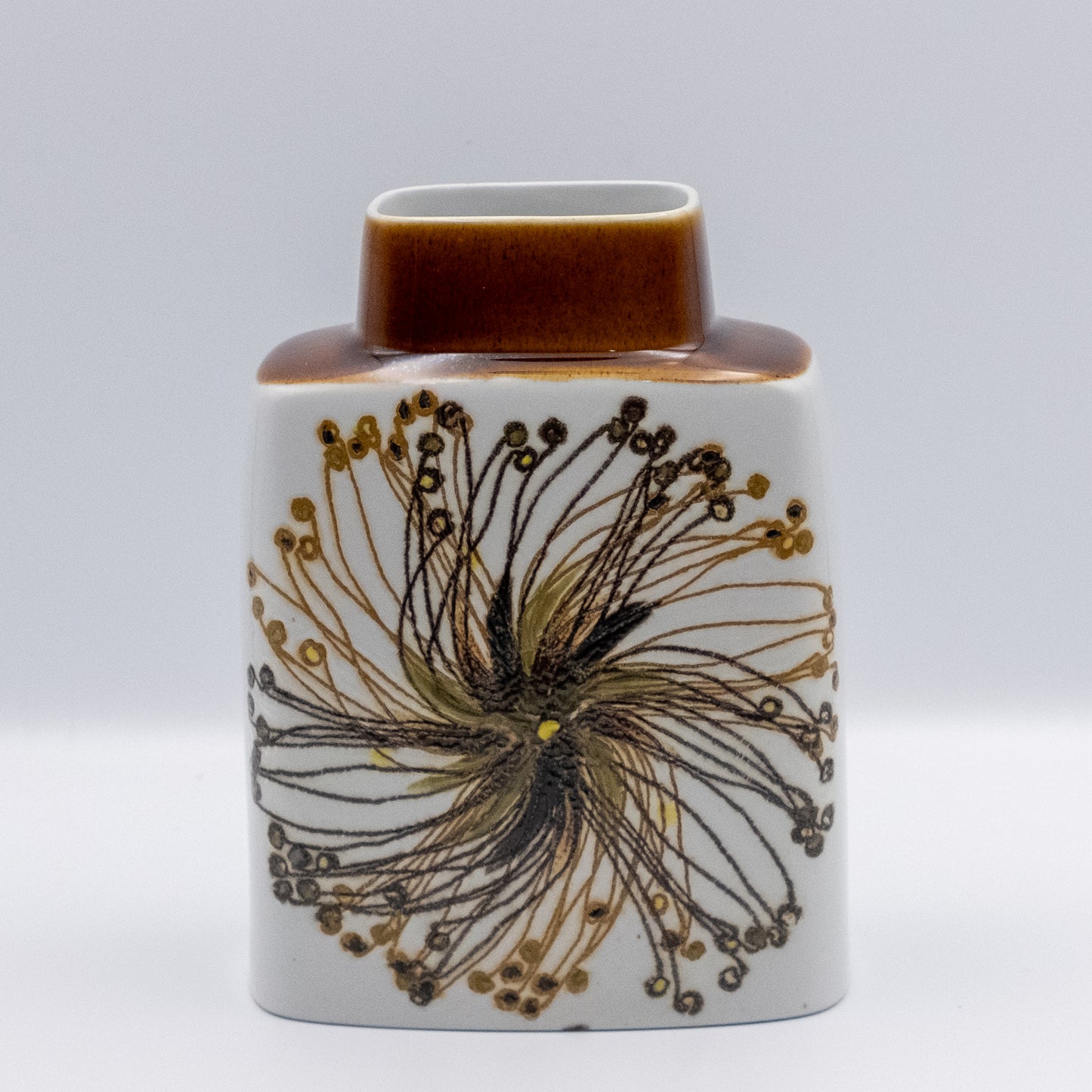 ロイヤルコペンハーゲン「バッカ（Baca）」シリーズのヴィンテージ花瓶。エレン・マルマーによる放射状の花模様。白地にブラウンと黄色の色彩、キャラメル色のネックが特徴のスクエア型。マットな質感と緻密な描線が美しい北欧陶器。